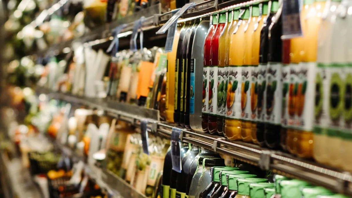 Prateleiras de mini mercado com bebidas organizadas e etiquetas de preços para conferência.