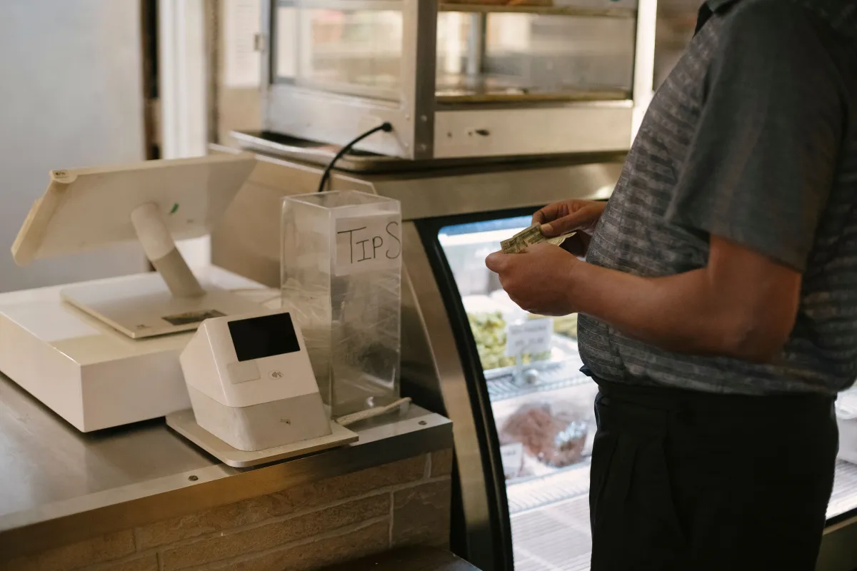 Cliente realizando pagamento em dinheiro em um caixa comercial.