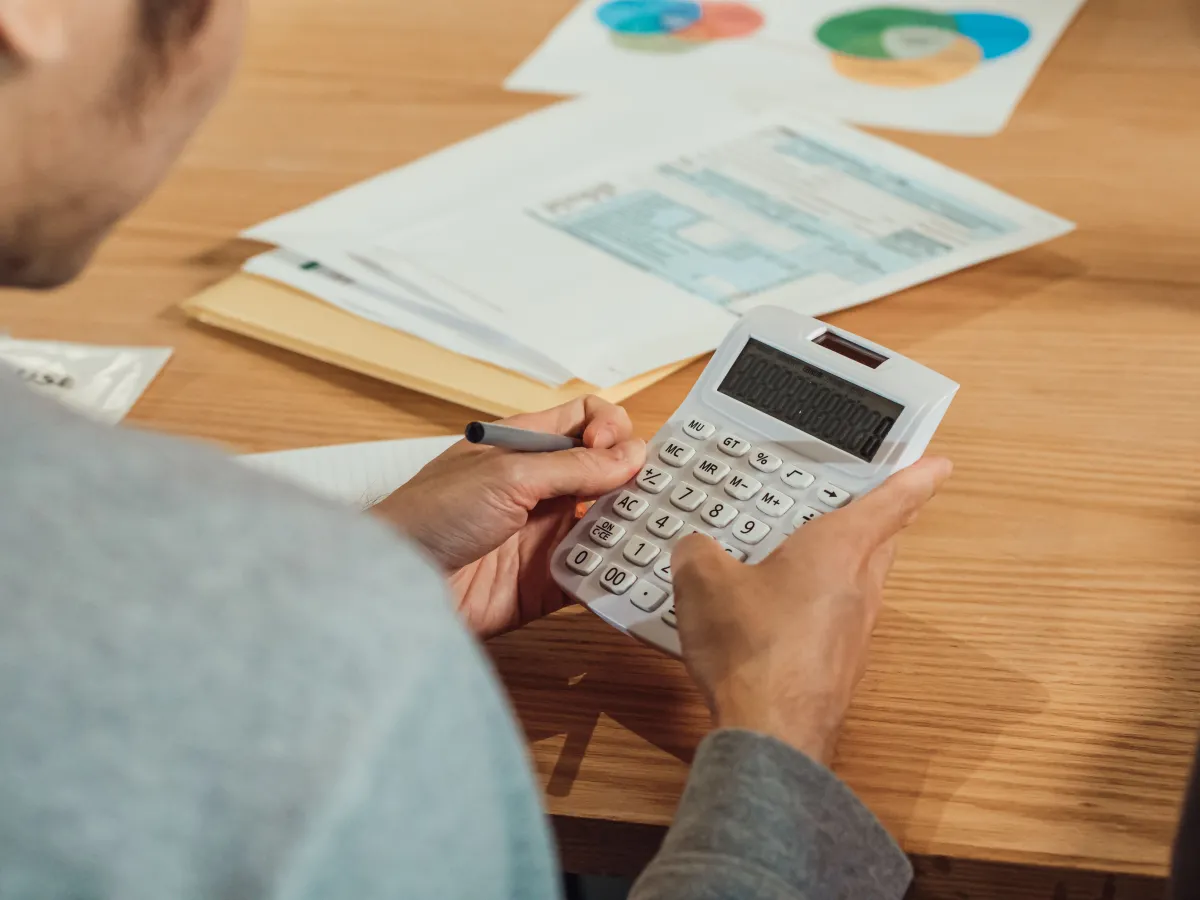Pessoa utilizando calculadora para conferir valores e documentos financeiros