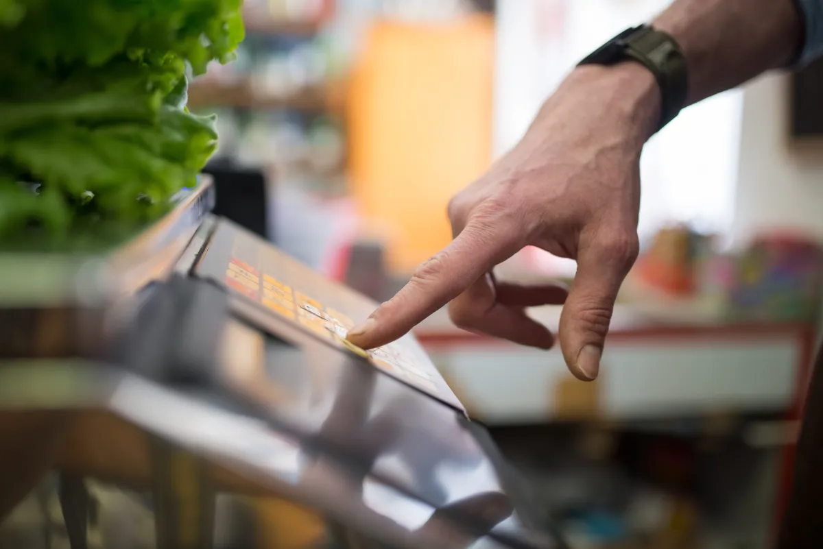 Pessoa utiliza balança digital para conferir a pesagem de produtos em estabelecimento comercial.
