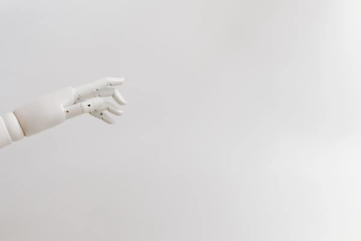 Mão artificial em tecnologia de prótese robótica com dedos articulados contra fundo branco, destacando o design mecânico e o movimento da articulação