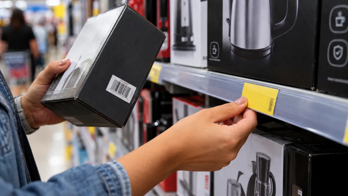 Pessoa conferindo a etiqueta de preço de um produto na prateleira de uma loja.
