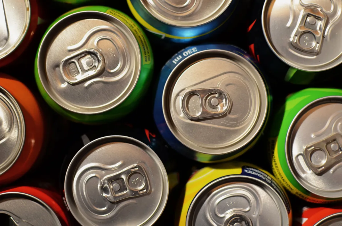 Fotografia de latas de bebidas organizadas, representando produtos comercializados em diferentes quantidades.