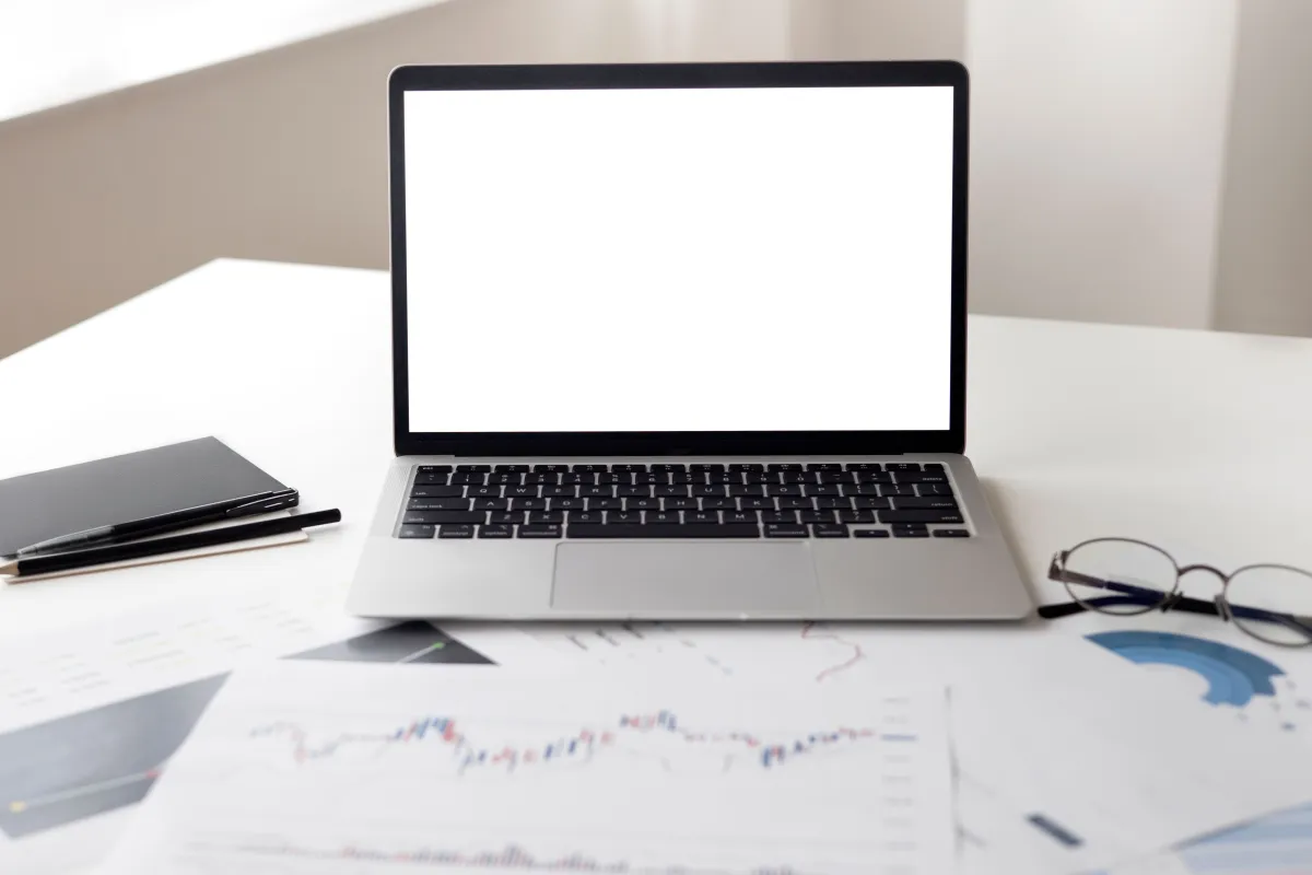 Computador e documentos utilizados na análise financeira e no acompanhamento de contas.