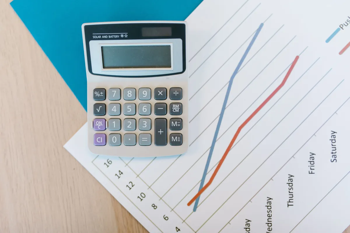 Calculadora financeira sobre gráfico com linhas e números, mostrando dados de planejamento e análise de desempenho