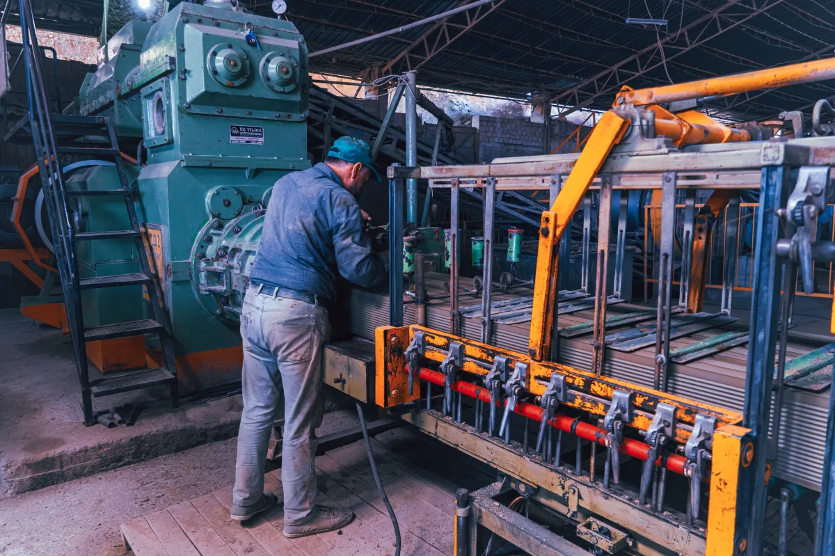 Trabalhador operando uma máquina em ambiente de fábrica.
