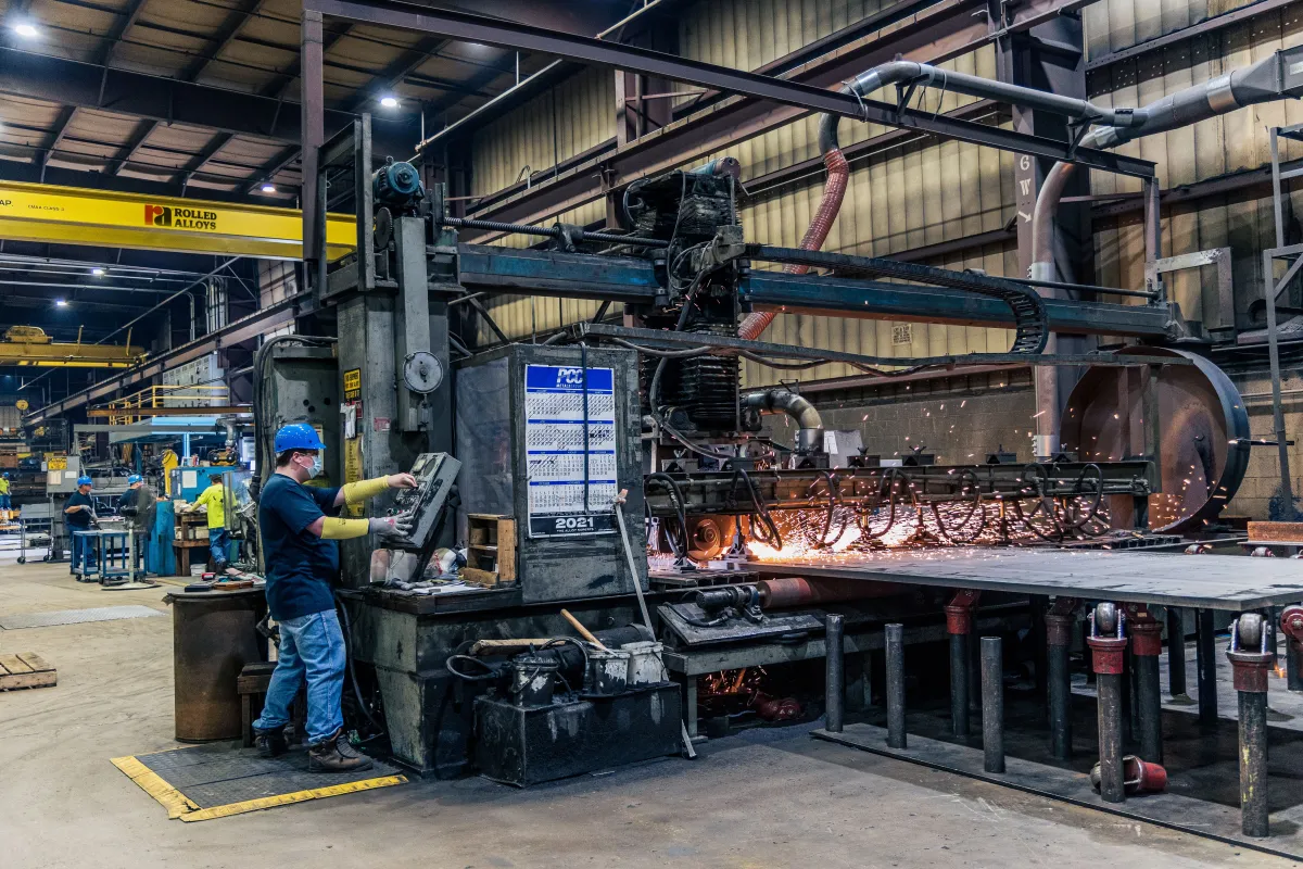 Trabalhador operando equipamentos em uma fábrica metalúrgica.