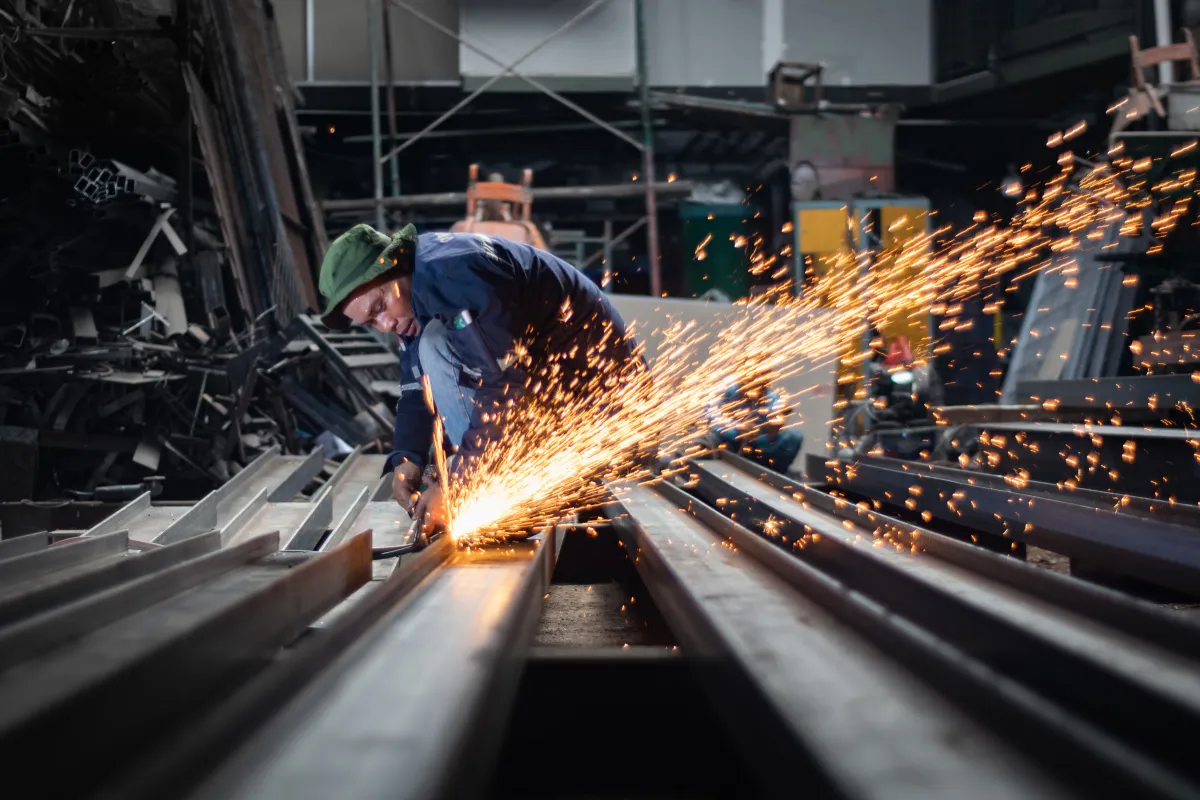 Máquina industrial realizando corte de chapa de aço na produção metalúrgica