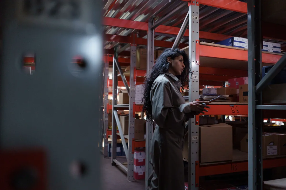 Funcionário realizando conferência física de caixas armazenadas no estoque industrial