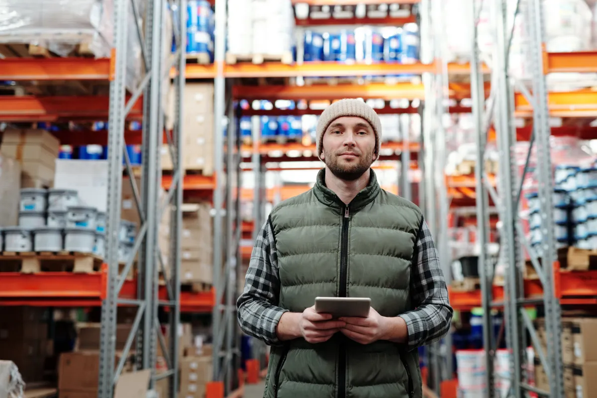 Supervisor conferindo a programação de produção em tablet ao lado de peças industriais