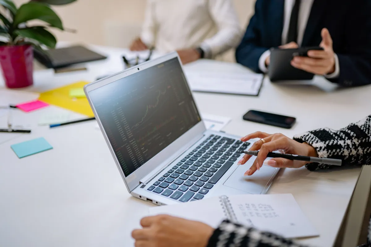Profissionais analisando informações em um notebook durante reunião de gestão empresarial