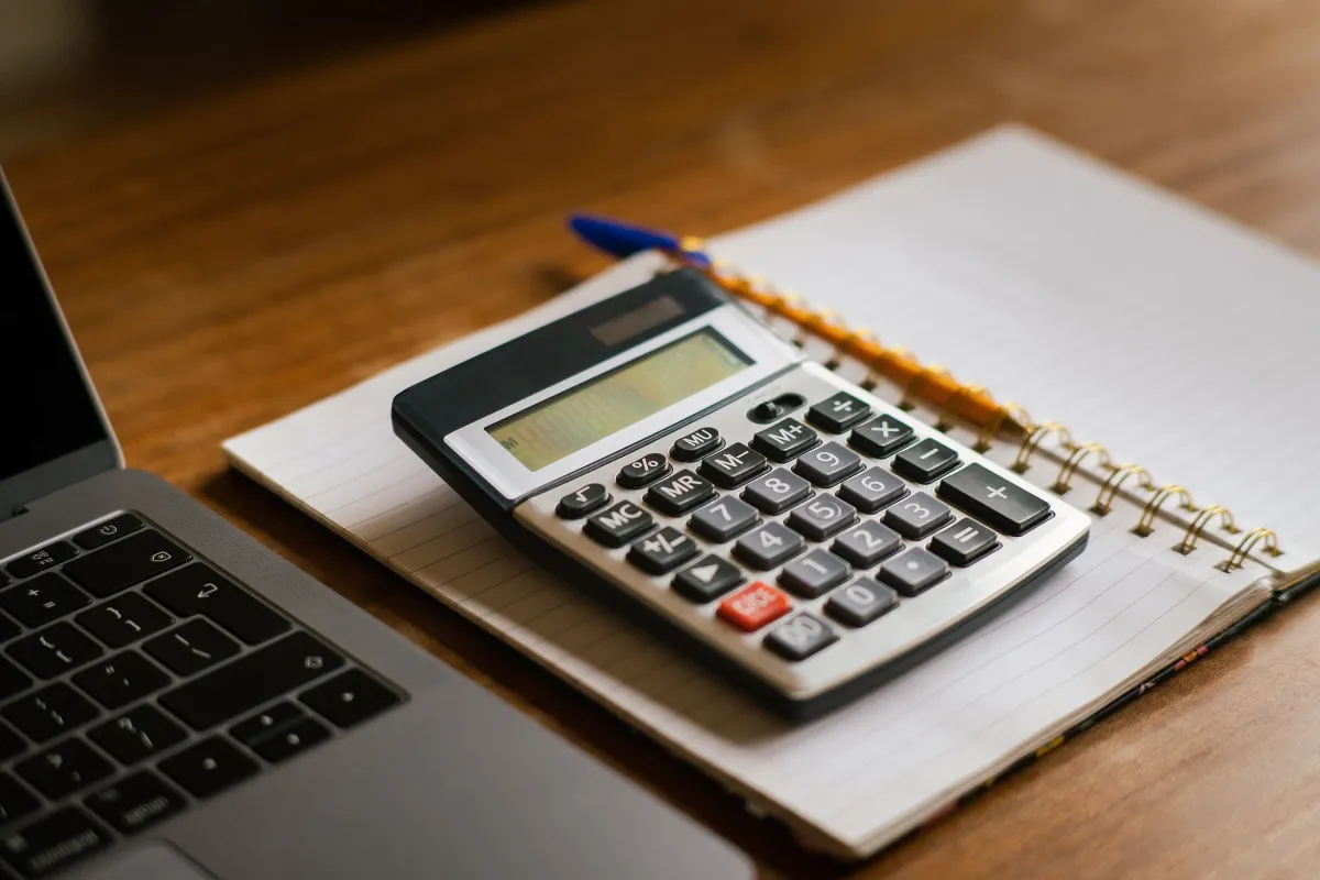 Mesa de trabalho com notebook e calculadora utilizados na organização de registros financeiros