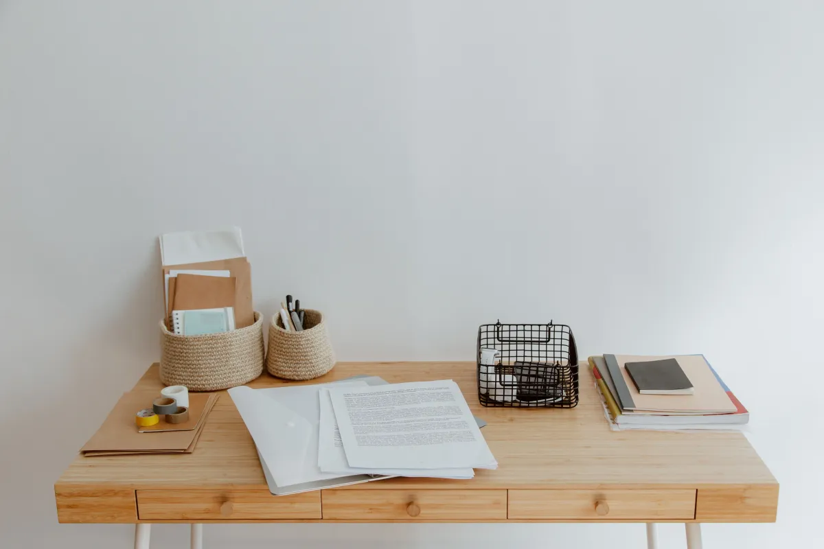 Mesa de escritório com documentos, pastas e materiais de papelaria organizados para atividades administrativas.