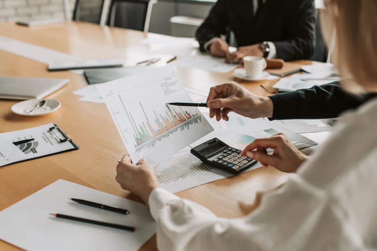 Profissional analisando relatórios de vendas e utilizando calculadora para conferir resultados financeiros.