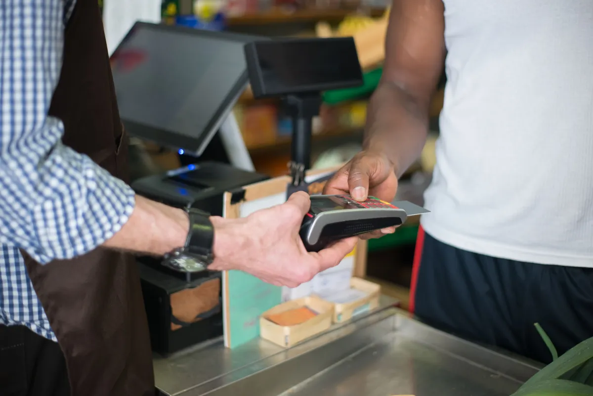 Cliente realizando pagamento com cartão em uma máquina de cartão no caixa de um estabelecimento comercial.