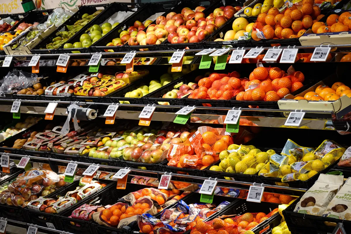 Variedade colorida de frutas frescas dispostas ordenadamente nas prateleiras do supermercado, ideal para temas de alimentação saudável.