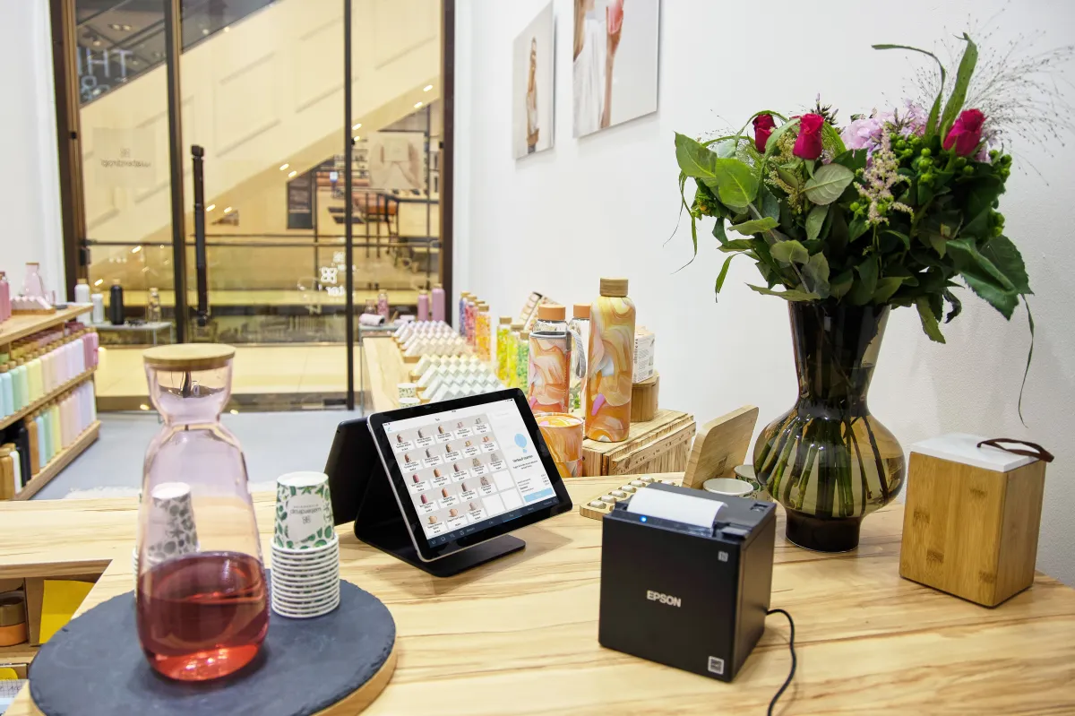 Fotografia de um caixa comercial moderno, com equipamento de pagamento e bancada organizada.