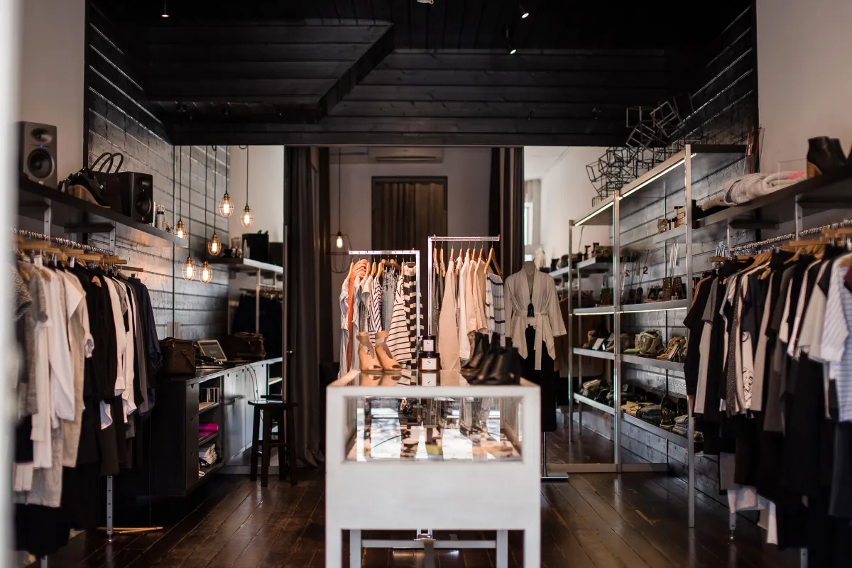 Interior de uma loja de roupas, com peças organizadas em expositores e ambiente comercial moderno.