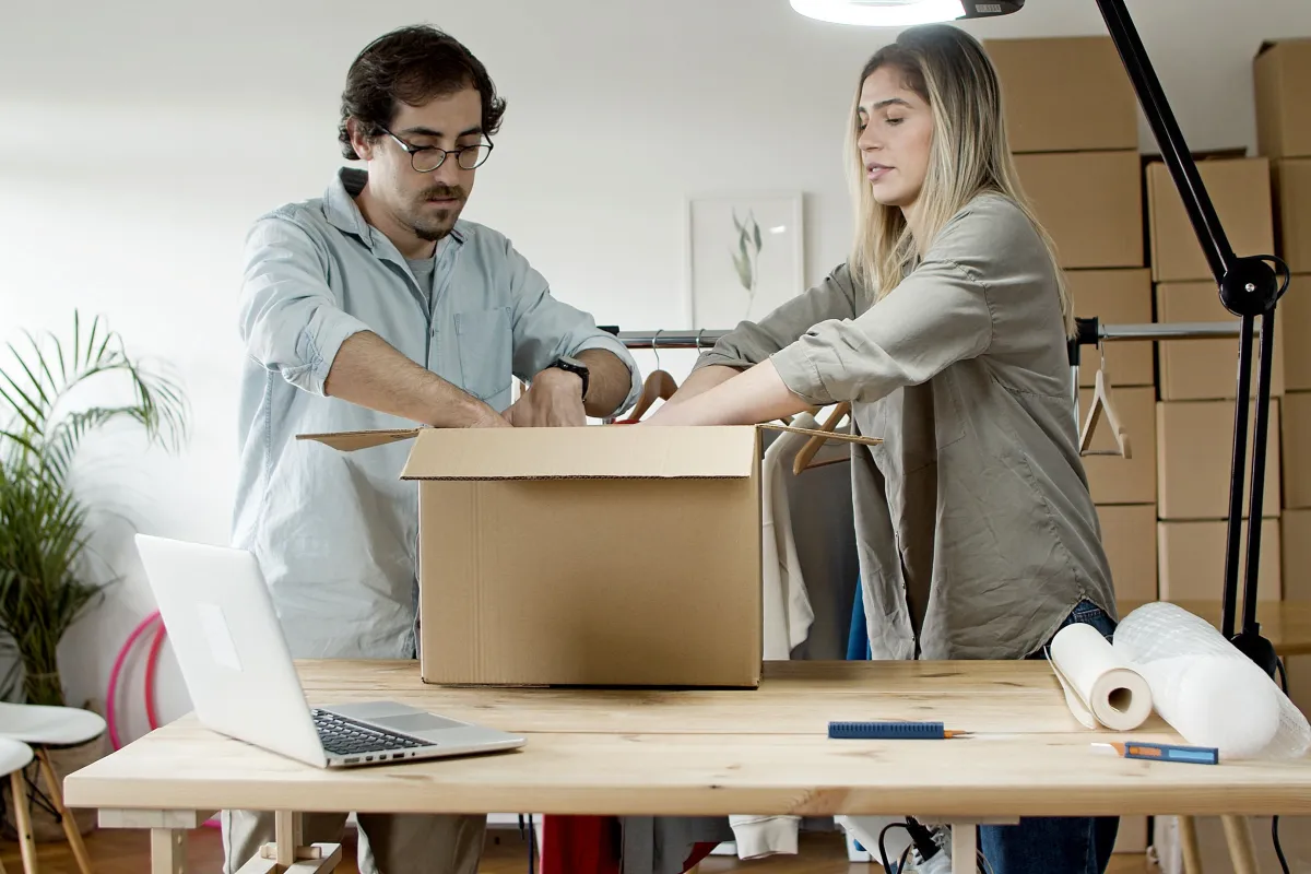 Preparação de pedidos de uma pequena loja virtual, com caixas e notebook.