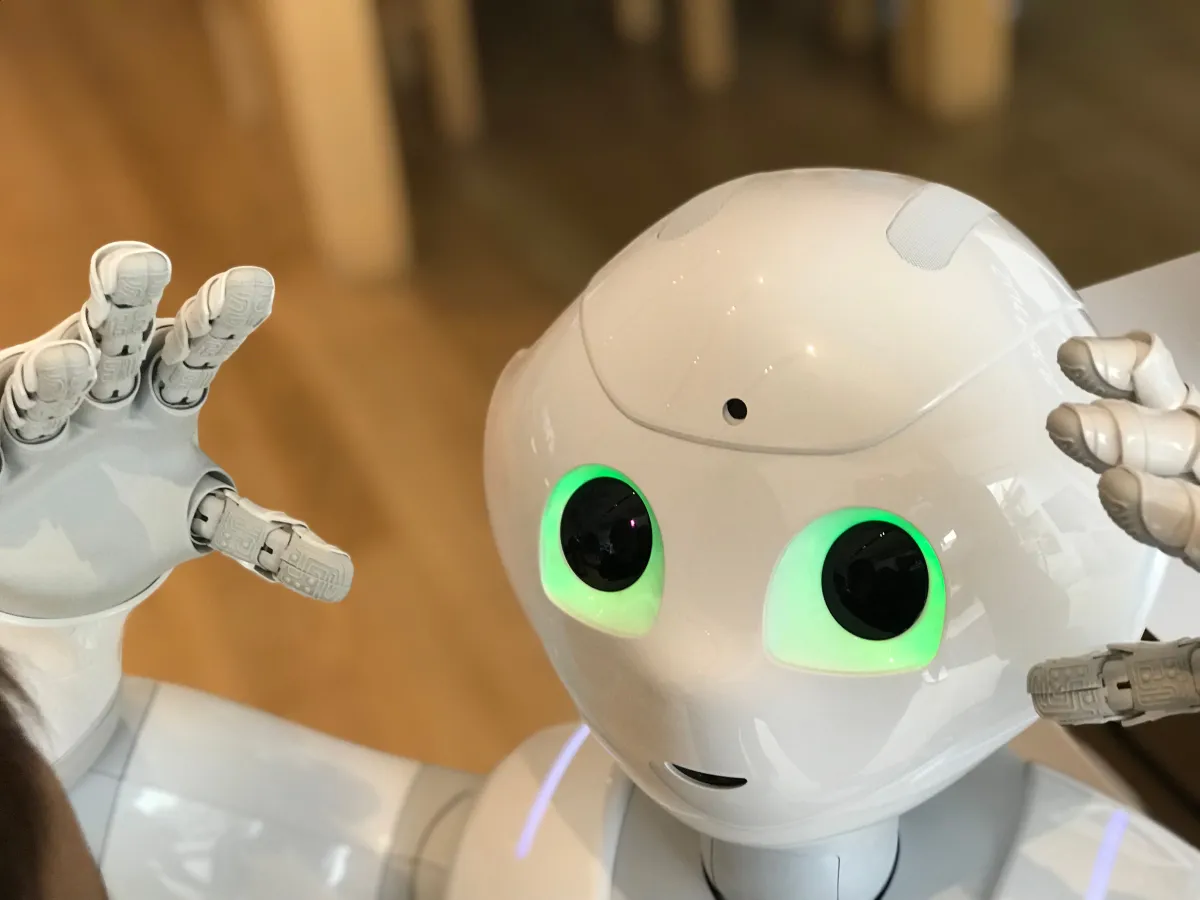 Robôs humanoides brancos com olhos luminosos verdes e expressão amigável, em ambiente interno; imagem associada a tecnologias de automação e inteligência artificial para Gestão com